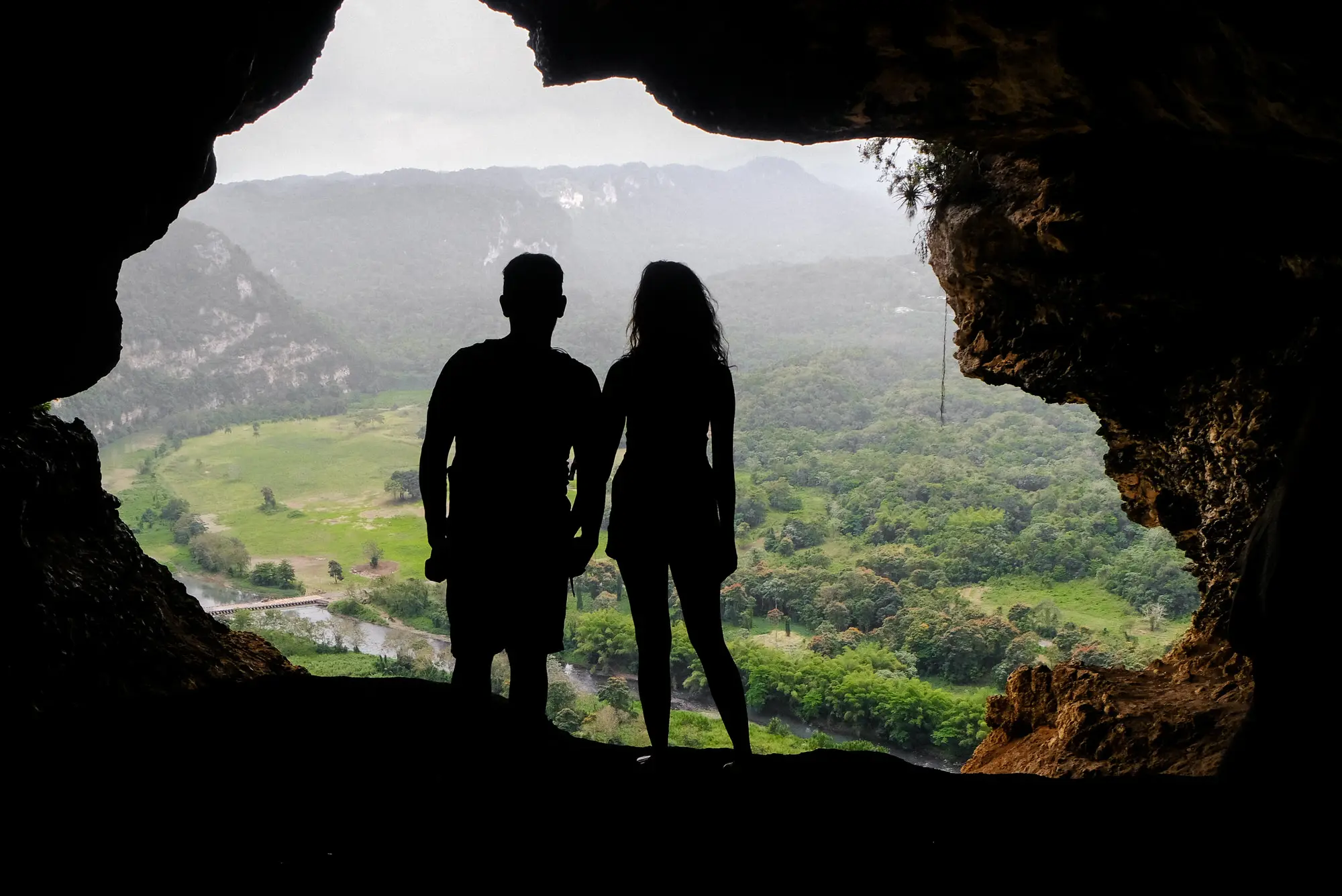 travel couple standing in window cave hike in puerto rico